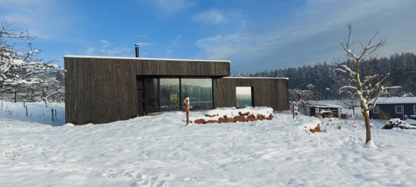 Neubau eines Einfamilienwohnhauses mit schwarzverkohlter Holzfassade im Schnee
