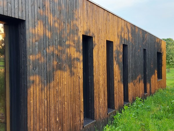 Abendsonne auf einer schwarzverkohlten Holzfasade als besonderes Designelement eines Neubau Einfamilienhauses. Architekturhighlight bei Gelnhausen im Main Kinzig Kreis