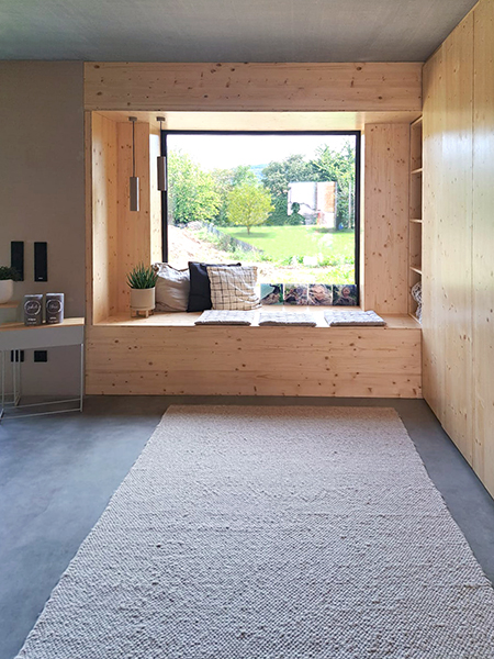 Gemütliches Sitzfenster voller Kissen in Alzenau, das als Schreinermöbel in das Garderobenmöbel des Eingangsbereiches übergeht.