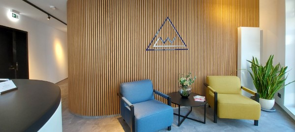 Büroplanung in Lohr am Main Empfangsbereich mit Sitzgelegenheiten und Holzlamellenwand passend zur Corporate Identity des Spessart