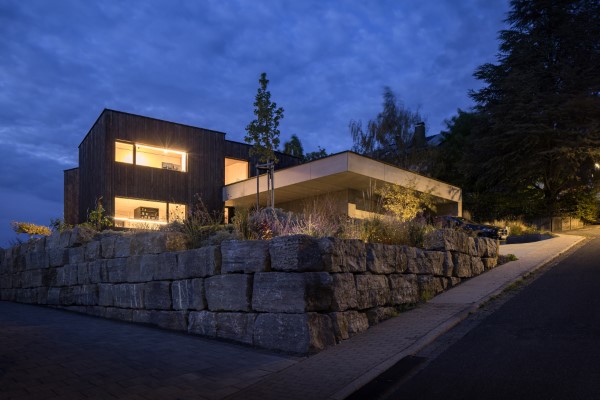 Außenaufnahme bei Abendlichtstimmung zeigt den Neubau eines Einfamilienhauses in Schöllkrippen bei Aschaffenburg. Reduzierte Formen sowie besondere Materialien bieten dem Architektenhaus einen besonderen Rahmen