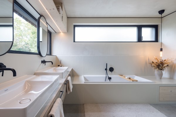Ein helles Badezimmer mit minimalsitischen Materialien und Farben, Doppelwaschbecken und beweglichen Spiegeln