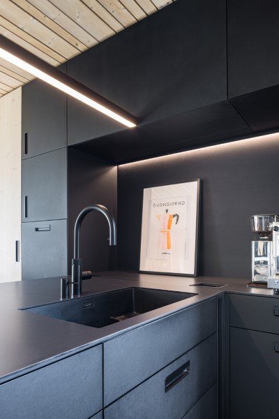 Nahaufnahme einer neugebauten Küche mit antrazithfarbenen Oberflächen sowie direkter und indirekter Beleuchtung